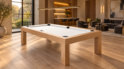 Natural white oak Rift pool table with white felt in a warm lounge with charcoal seating and an illuminated bar.